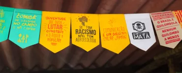 Bandeirinhas com mensagens político-sociais enfeitam a estrutura da feira, reforçando causas que caminham lado a lado à agroecologia e ao direito de comer bem.