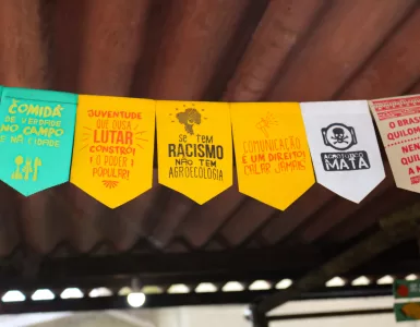 Bandeirinhas com mensagens político-sociais enfeitam a estrutura da feira, reforçando causas que caminham lado a lado à agroecologia e ao direito de comer bem.