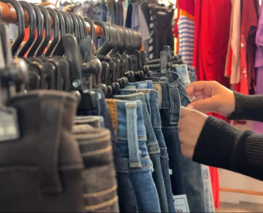 Pessoa seleciona roupas em arara de brechó em Belo Horizonte