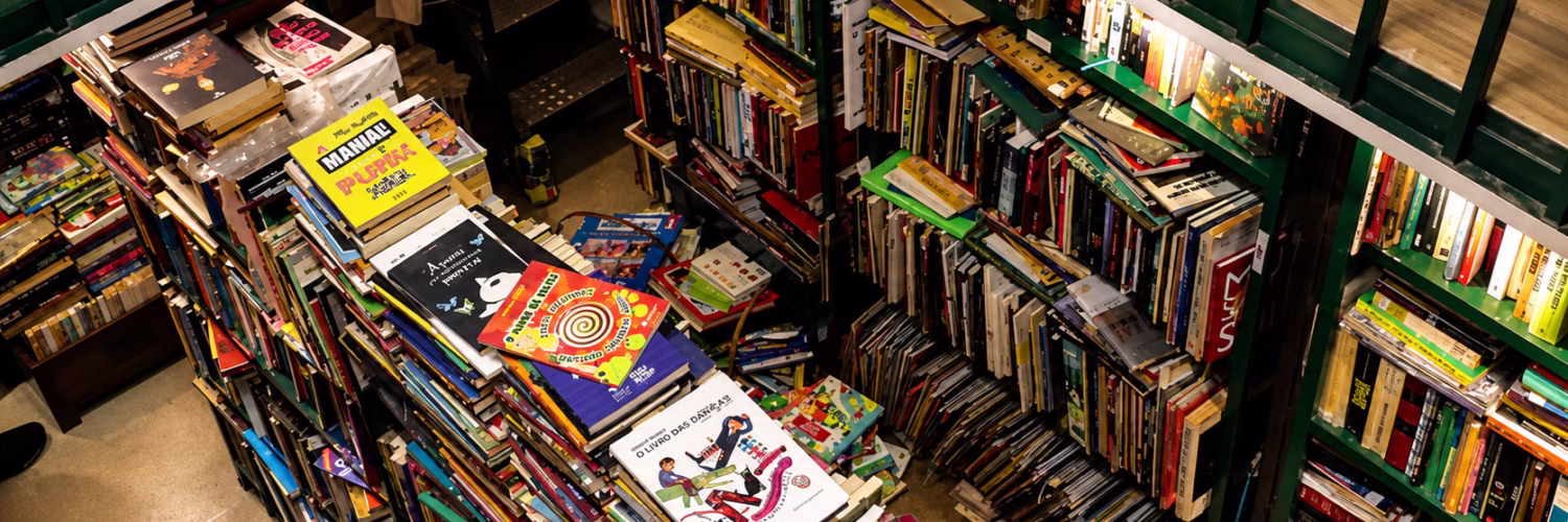 Interior do Sebo Poesis com estantes repletas de livros e revistas organizados em prateleiras.